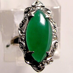 May include: A silver ring with a green gemstone set in a marcasite design.