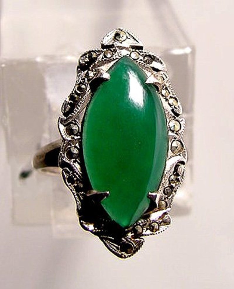 May include: A silver ring with a green gemstone set in a marcasite design.