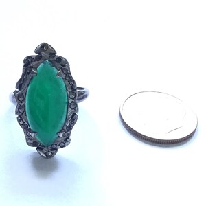 May include: A silver ring with a green gemstone set in a black marcasite design.