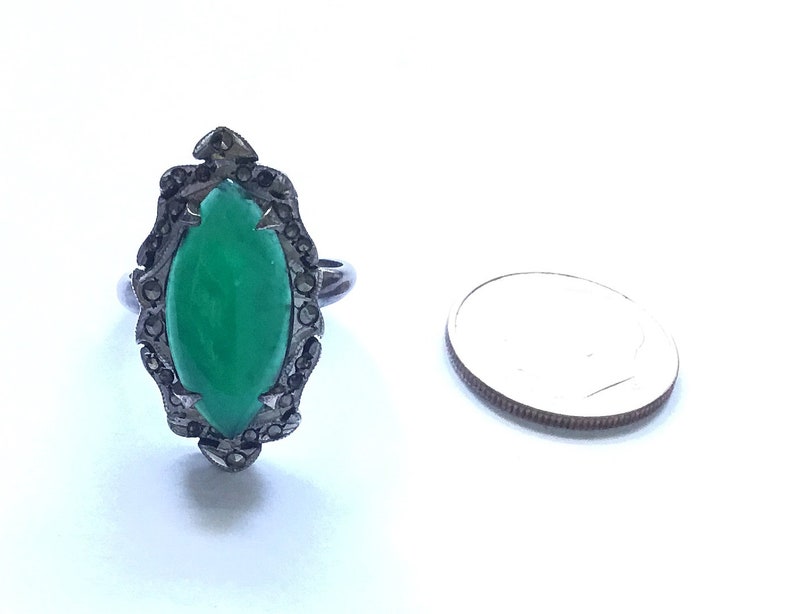 May include: A silver ring with a green gemstone set in a black marcasite design.
