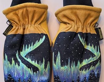 May include: A pair of yellow leather mittens with a black cuff and a painted design of the Northern Lights. The design features a black sky with white stars, green and blue aurora borealis, and a forest silhouette.