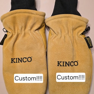 May include: A pair of yellow suede Kinco mittens with black knit cuffs. Each mitten features the black text KINCO and a white rectangular label with the black text Custom!!!!. A small black Heatkeep tag is visible on the right mitten.