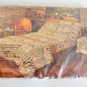May include: A close-up of a zebra print twin flat sheet packaged in plastic. The sheet is brown and white with a zebra print pattern. The packaging includes instructions for washing and hemming the sheet.