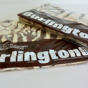 May include: Two packages of Burlington twin flat sheets in plastic packaging. The sheets feature a brown and white zebra print. The packaging includes the text "One twin flat sheet for 30x75 in. to 39x75 in. mattress (66x104 in. size before hemming)" and "Burlington Domestics, a division of Burlington Industries, Inc., New York, N.Y. 10001."