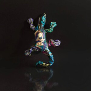 May include: A colorful, hand-painted ceramic lizard figurine with a human face and floral patterns in shades of blue, green, purple, and gold.