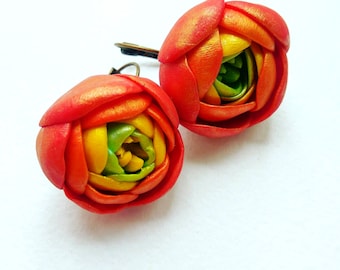 Op de afbeelding: Een paar rode, gele en groene polymer clay oorbellen in de vorm van bloemen. De oorbellen zijn handgemaakt en hebben een delicate, vrouwelijke uitstraling.