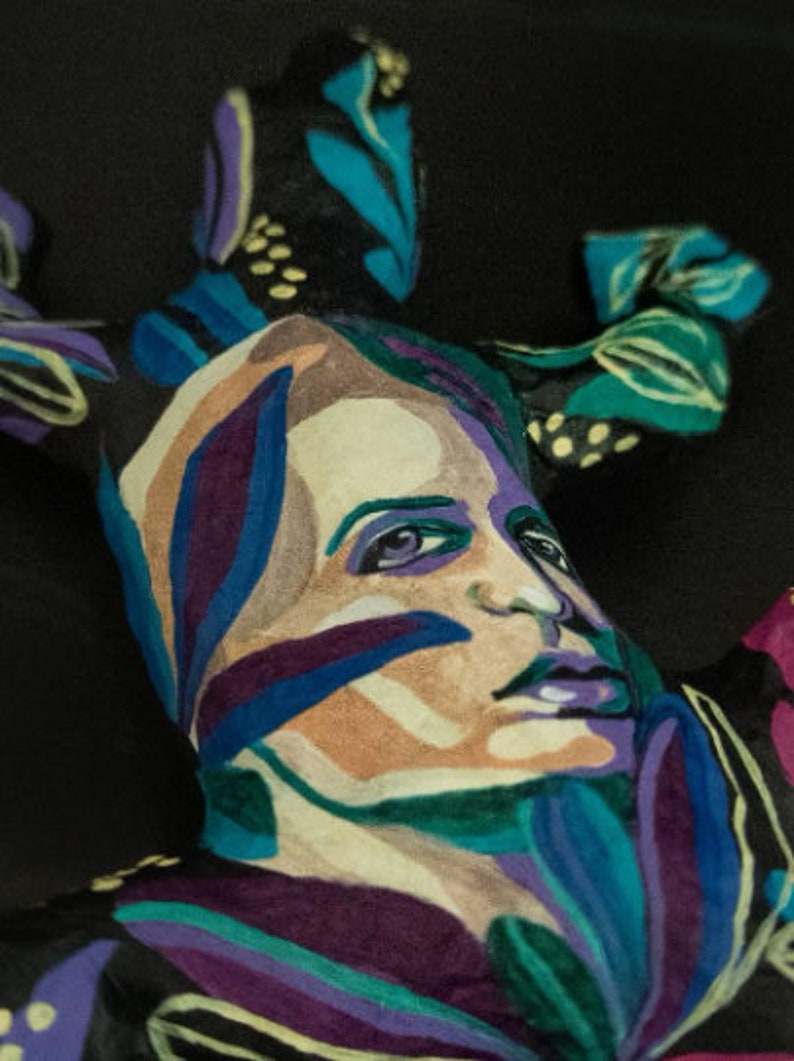 May include: A colorful abstract painting of a face with blue, green, purple, and white paint. The face is surrounded by abstract shapes and patterns.