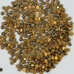 May include: A large quantity of gold-colored round rhinestones. The rhinestones have a faceted surface and a metallic finish.