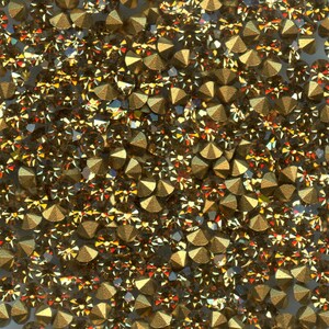 Peut inclure: Une grande collection de petits cristaux facettés en forme de cône avec une finition dorée métallique. Chaque cristal présente un sommet pointu et de multiples facettes triangulaires qui reflètent la lumière, créant une surface dense et texturée.
