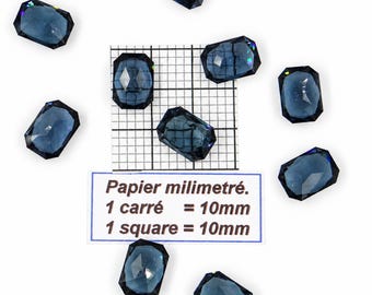 Puede incluir: Nueve piedras preciosas rectangulares de color azul oscuro con facetas dispuestas alrededor de una escala de papel milimetrado. El papel incluye el texto: Papier millimétré. 1 carré = 10mm. 1 square = 10mm. Cada piedra tiene una superficie pulida.