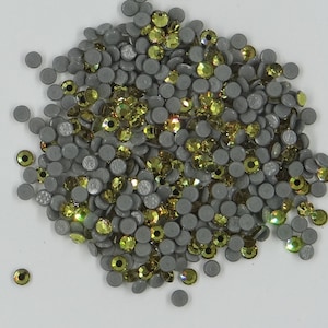 Peut inclure: Un ensemble de strass gris à dos plat et de strass vert olive irisés. Les strass sont dispersés sur la surface, créant un aspect texturé. Ces embellissements conviennent à divers projets d'artisanat.