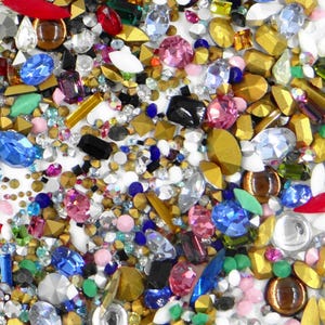 Peut inclure: Un grand assortiment de strass et de perles en verre de différentes formes et tailles. Les strass sont de couleur rouge, bleu, vert, rose, or et transparent. Les perles sont de couleur marron, or et transparent.