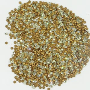 Peut inclure: Un grand tas de strass dorés et transparents. Les strass sont petits et ont un sommet pointu.