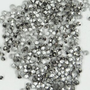 Peut inclure: Gros plan sur une grande quantité de petits strass de couleur argent. Les strass ont une forme facetée et pointue.