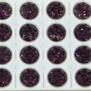 Peut inclure: Une feuille de 20 pierres précieuses rondes, facettées, de couleur violette dans un plateau en plastique blanc. Les pierres précieuses sont disposées en forme de grille.