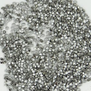 Peut inclure: Gros plan d'un tas de strass de couleur argent. Les strass sont petits et ont un design facetté.