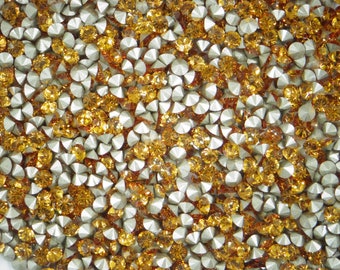 Puede incluir: Una imagen de primer plano de una gran cantidad de pequeños diamantes de imitación redondos y facetados. Los diamantes de imitación son una mezcla de colores dorado y plateado.