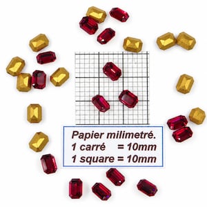 Peut inclure: Une collection de pierres précieuses rectangulaires à facettes rouges et de perles rectangulaires dorées mates disposées autour d'un papier millimétré. Le papier porte le texte : Papier millimétré. 1 carré = 10mm. 1 square = 10mm.