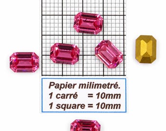 Puede incluir: Cinco piedras preciosas rectangulares facetadas, cuatro en un rosa vibrante y una con acabado dorado mate. Las piedras están dispuestas alrededor de una cuadrícula con el texto Papier milimétré, 1 carré = 10mm, 1 square = 10mm como referencia.