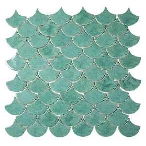 May include: A square of teal-coloured, fan-shaped tiles arranged in a repeating pattern. The tiles have a glossy finish and are reminiscent of fish scales. The grout lines are a light colour, creating contrast. Suitable for a bathroom or kitchen.