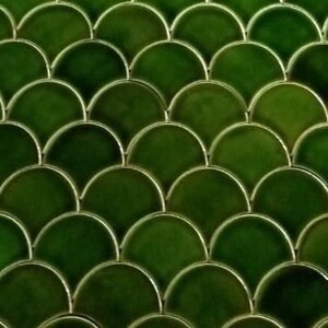 Op de afbeelding: Groene keramische tegels in een visgraatpatroon. De tegels zijn glanzend en hebben een lichte glans.