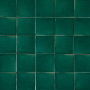 Puede incluir: Una pared enlosada con azulejos cuadrados de cerámica verde oscuro.
