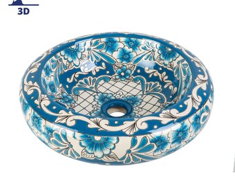 May include: A round, white ceramic sink with a blue and white floral design. The sink has a single drain hole in the center.