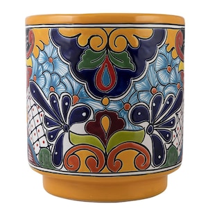 May include: A yellow ceramic planter with a colourful floral and geometric design. The planter has a wide base and a cylindrical shape.