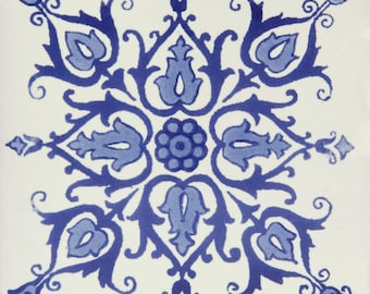 May include: A blue and white ceramic tile with a symmetrical floral pattern. The design features intricate swirls and leaves, creating a traditional and elegant look.