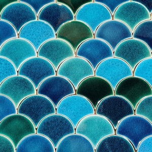 Puede incluir: Primer plano de una pared cubierta con azulejos de cerámica azul y verde. Los azulejos están dispuestos en un patrón de escamas de pez.