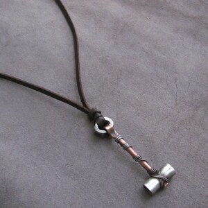 May include: A brown leather cord necklace with a silver and copper hammer pendant.