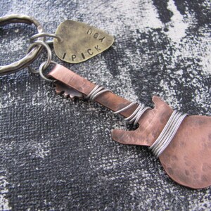May include: A copper guitar-shaped keychain with a silver key ring and a brass tag that says "I pick you".