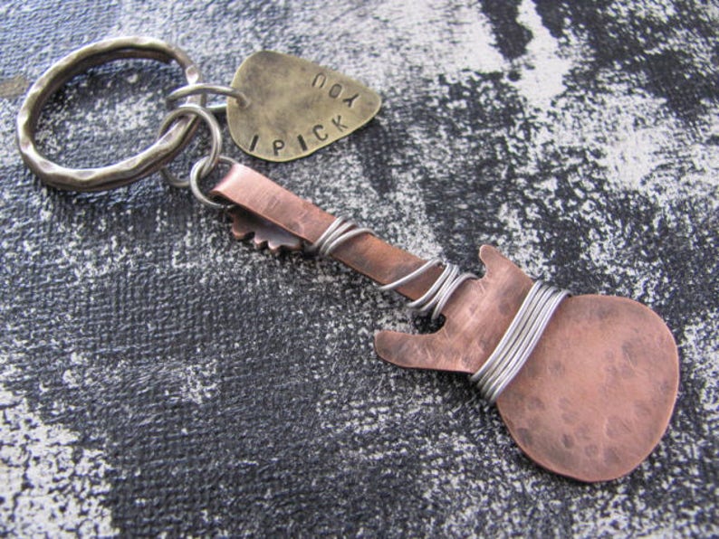 May include: A copper guitar-shaped keychain with a silver key ring and a brass tag that says "I pick you".