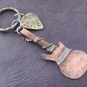May include: A copper guitar-shaped keychain with a silver key ring and a silver pick charm that says "I Pick You".