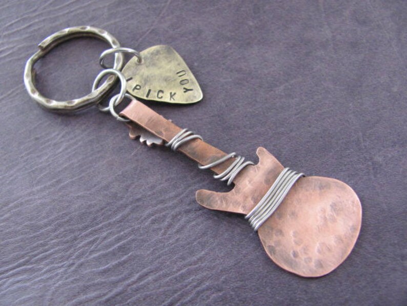 May include: A copper guitar-shaped keychain with a silver key ring and a silver pick charm that says "I Pick You".