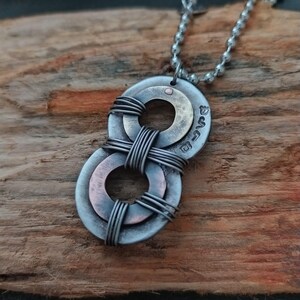 May include: A silver necklace with a pendant made of two stacked metal washers. The washers are connected by wire and have a copper finish. The pendant is inscribed with the word "Love".