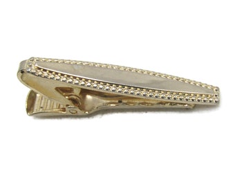 May include: A gold-toned tie clip with a rectangular center and a beaded border. The clip has a hinged design for securing to a tie. The overall design is simple and elegant, suitable for formal wear.