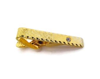 May include: Gold tie clip with a textured design and a single clear rhinestone.