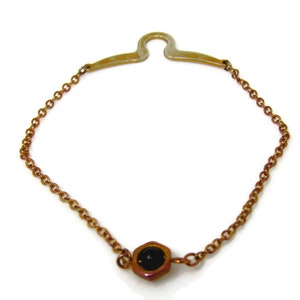 May include: A gold chain necklace with a black stone pendant. The pendant is shaped like a hexagon.