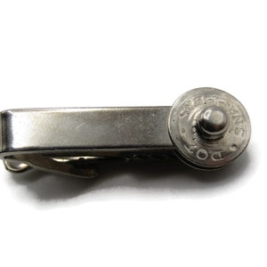 May include: Silver tie clip with a round, engraved top that says "Swiss Made DOT".