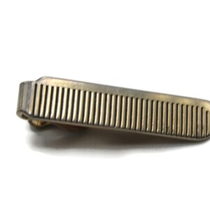 May include: A silver tie clip with a ridged design.