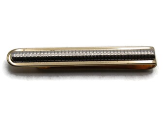 May include: A gold tie clip with a silver textured band.