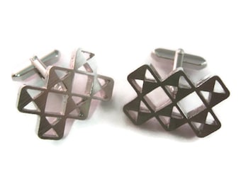 May include: A pair of silver-toned cufflinks with an open geometric design. Each cufflink features a cross-like shape with multiple triangular cutouts. The cufflinks have a shiny, metallic finish and a classic post closure.