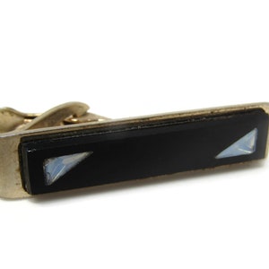 May include: A silver tie clip with a black rectangular inlay and two clear rhinestones.