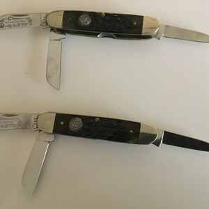 May include: Two Case brand pocket knives with black handles and silver blades. The knives have a decorative design on the blades and a Case logo on the handles.