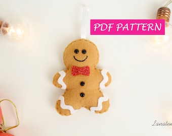 May include: A felt gingerbread man ornament with a red bow tie, white icing, and black button eyes. The ornament is hanging from a white string and has the text "PDF PATTERN" in pink letters above it.