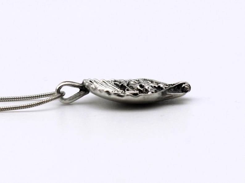 May include: Silver-toned pendant necklace with a detailed, ornate design. The pendant is a small, shallow dish shape with intricate patterns. The necklace chain is a thin, silver snake chain. The pendant is approximately 1 inch in length.