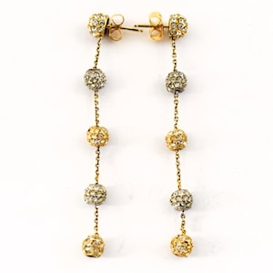 May include: A pair of long gold earrings with dangling crystal-encrusted balls. Each earring has five balls, alternating between gold and silver.