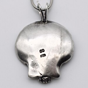 May include: A silver pendant with a pomegranate design, attached to a silver chain. The pendant has a textured surface and a small, detailed base. The back of the pendant has the markings "GD" and "STER".