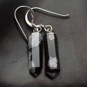 May include: A pair of silver dangle earrings with black and white snowflake obsidian gemstone drops.